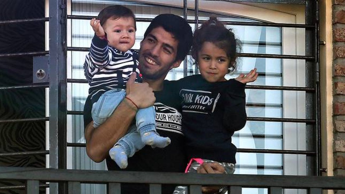 Luis Suárez, acompañado de sus hijos, saluda a los aficionados uruguayos apostados ante su casa cerca de Montevideo.