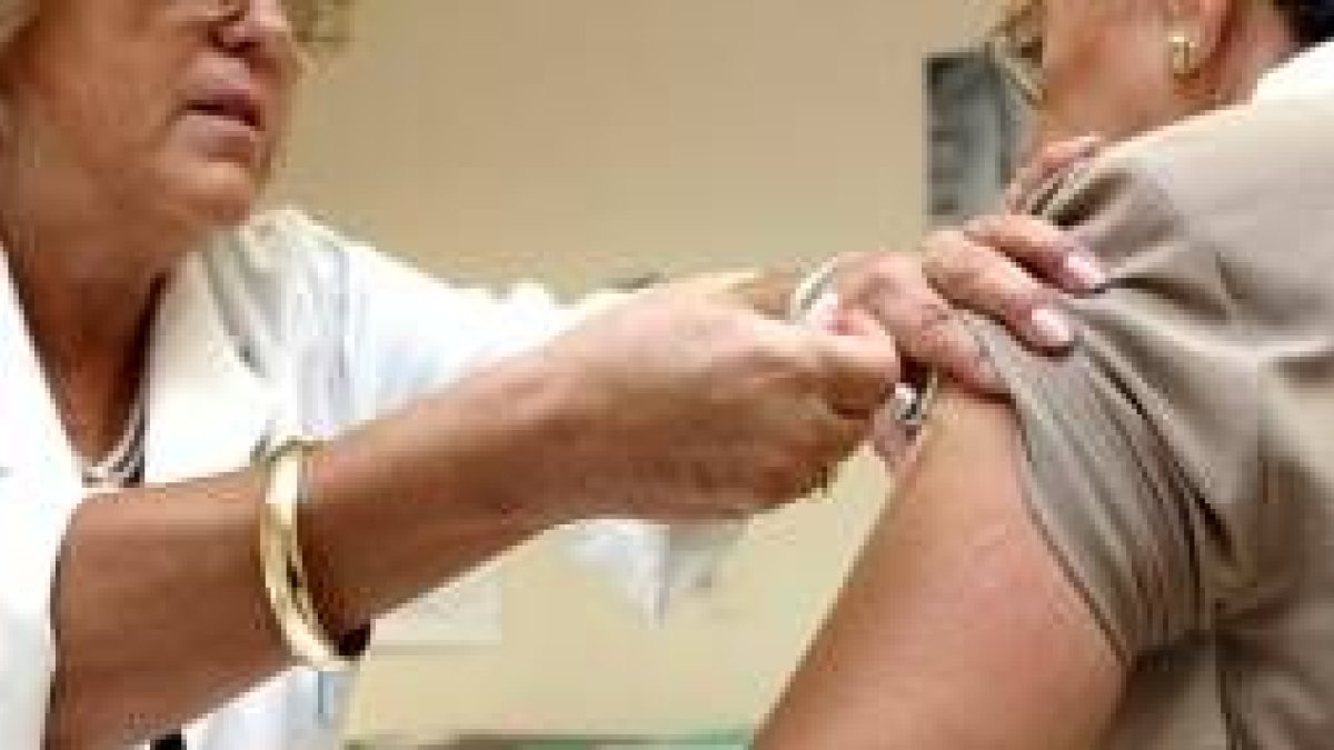 Una enfermera pone una vacuna contra la gripe a una paciente