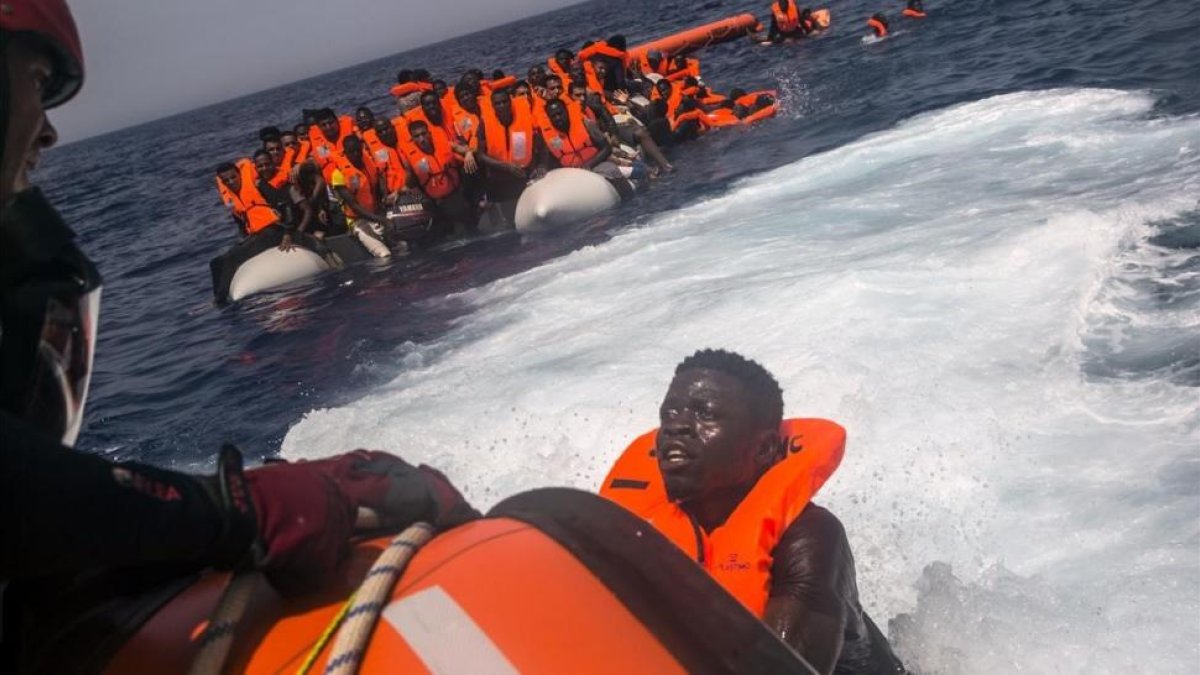 Un inmigrante africano trata de subir al barco de Proactiva Open Arms
