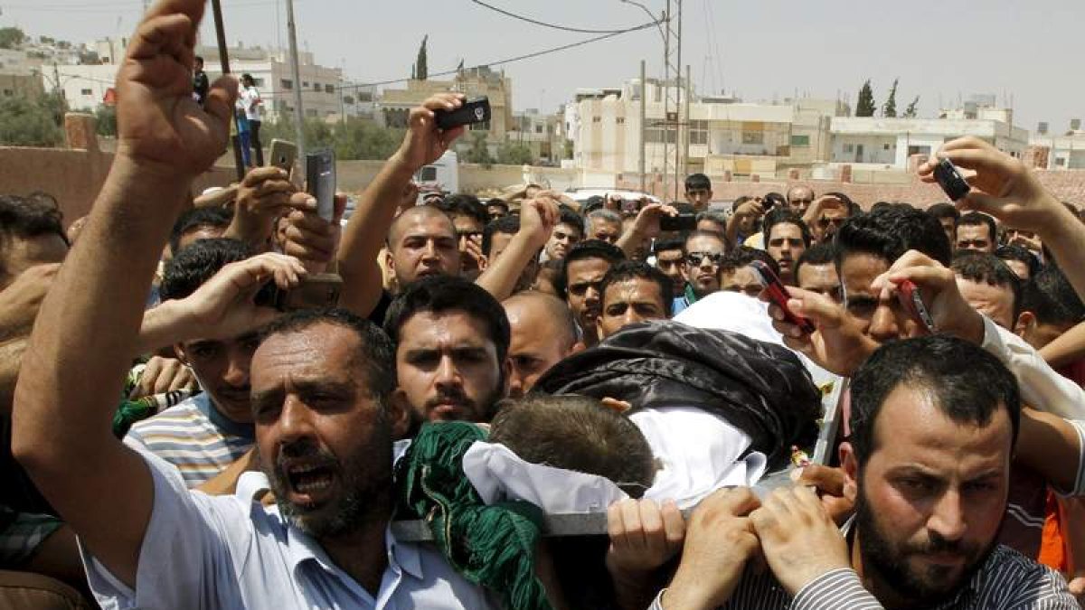 Varios jordanos y residentes sirios cargan con el cadáver de un niño tiroteado cuando huía.