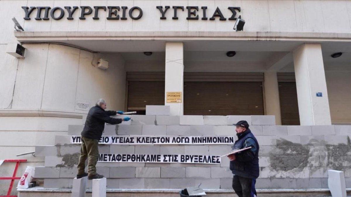 Manifestantes levantan un muro en la sede del Ministerio de Sanidad de Grecia con la inscripción 'Cerrado por el rescate. Hemos sido trasladados a Bruselas', en una protesta contra la austeridad en Atenas, en diciembre del 2016.