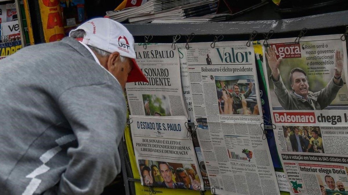 Un hombre lee en la prensa noticias sobre la victoria de Bolsonaro.
