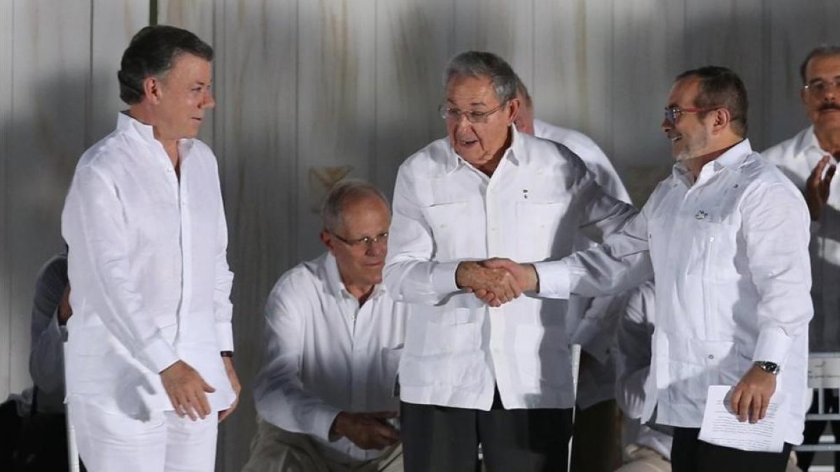 Raúl Castro, presidente de Cuba (centro) da la mano al comandante jefe de las FARC, Rodrigo Londoño, en presencia del presidente de Colombia, Juan Manuel Santos, en Cartagena de Indias, el 26 de septiembre.