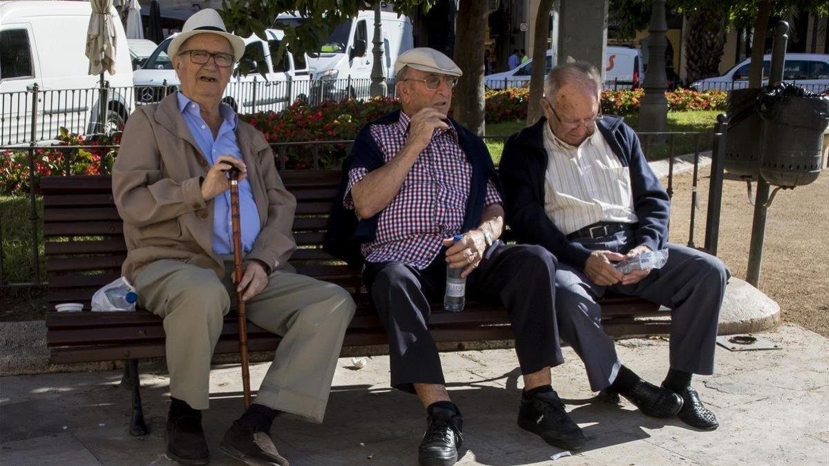 Tres jubilados descansan en un banco de un parque en Valencia.
