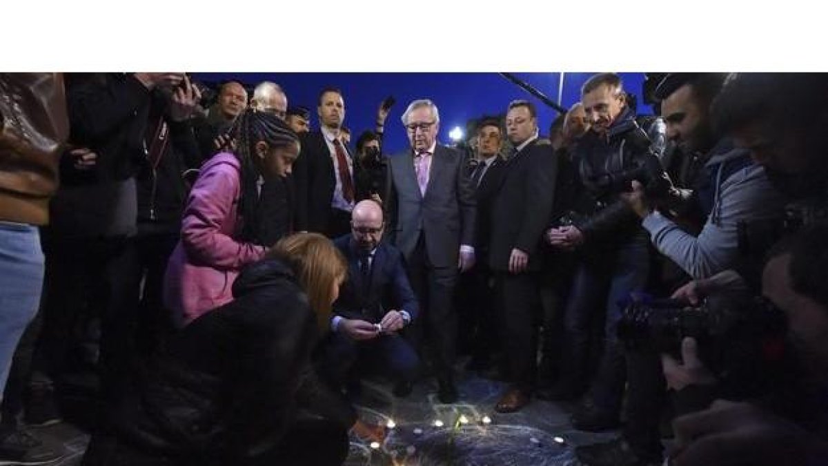 el primer ministro Charles Michel (c-i) y el presidente de la Comisión Europea Jean-Claude Juncker (c-d) encienden velas en la plaza Bourse como tributo a las víctimas de los atentados terroristas