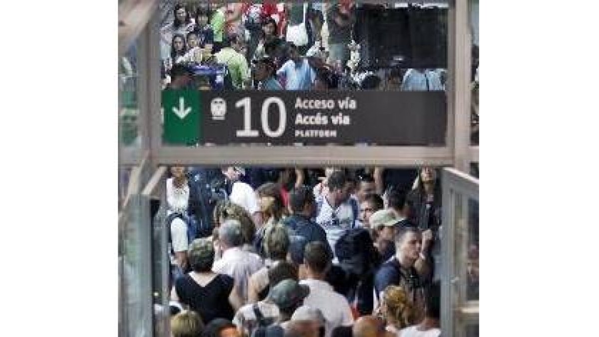 Numerosos pasajeros esperan en los andenes en la estación de Sants