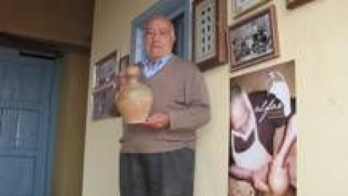 El maestro alfarero, Martín Cordero, posa junto a uno de los carteles promocionales del museo