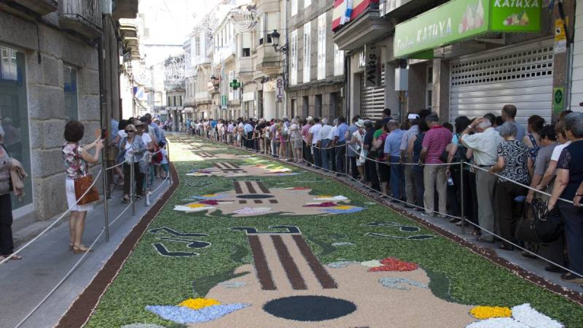 Varias personas junto a una alfombra floral que decora una de las calles de Ponteareas, con motivo de la celebración del Corpus Christi.