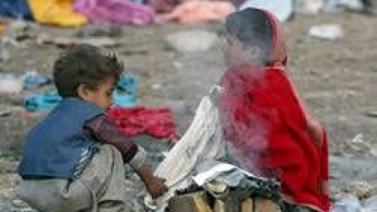 Dos niños supervivientes del terremoto encienden fuego en un asentamiento de refugiados, en Balakot