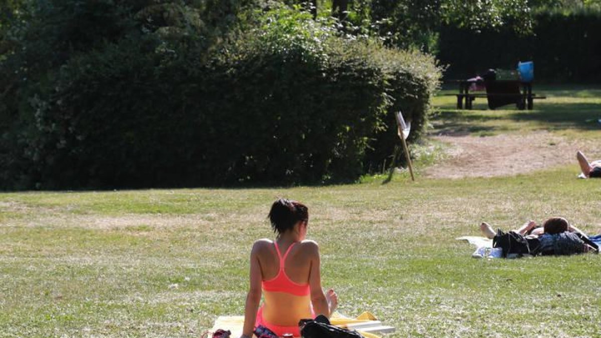 Una chica toma el sol en un parque de León