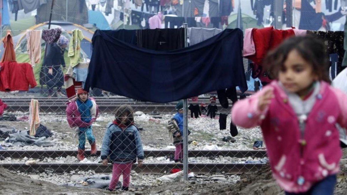 Niños refugiados juegan entre ropas colgadas para secar entre alambradas en un campo de refugiados de Idomeni (Grecia), junto a la frontera con Macedonia, este miércoles.