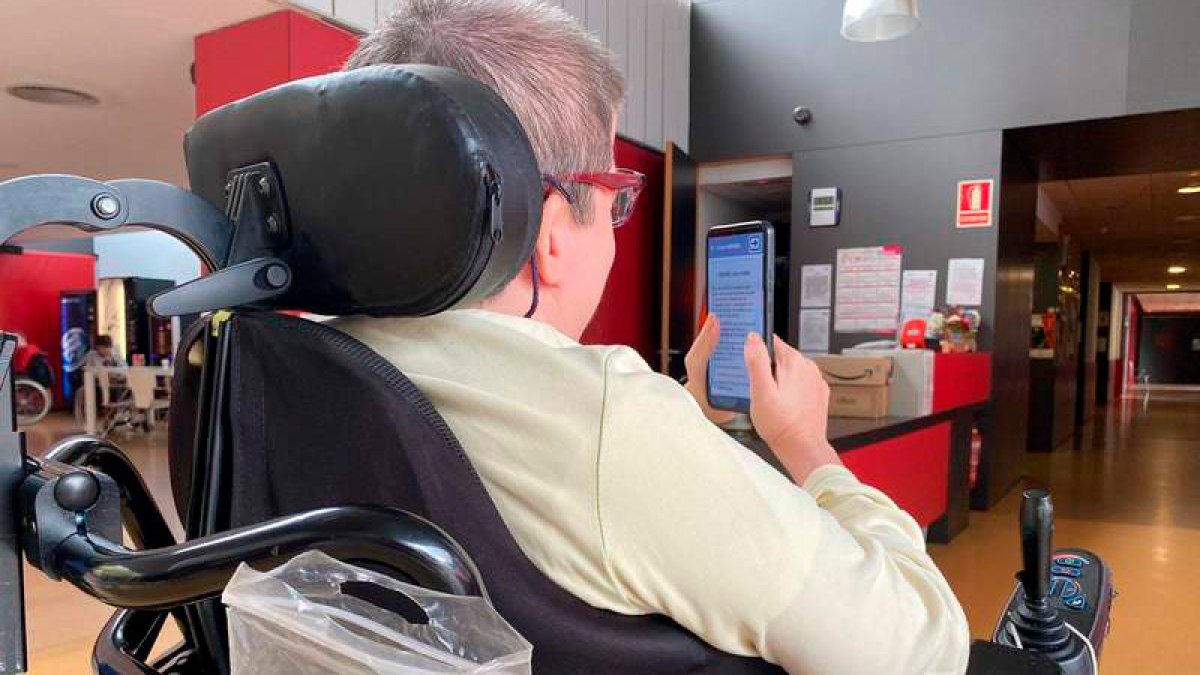 Una mujer con discapacidad física consulta la app Vela de Aspaym. DL