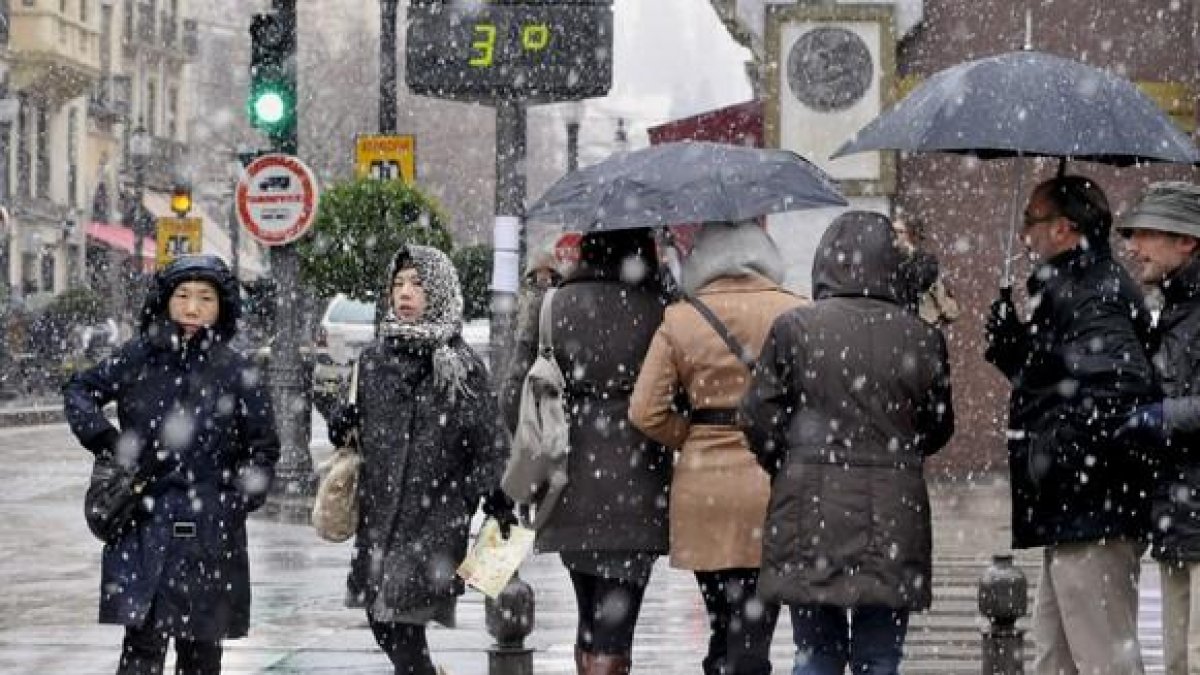 Varias personas pasean por una céntrica calle de Granada a pesar de la nieve que ha caído en las últimas horas en la ciudad, donde se ha declarado la alerta amarilla debido a las consecuencia del temporal de viento, frío y nieve que afecta a casi todo el