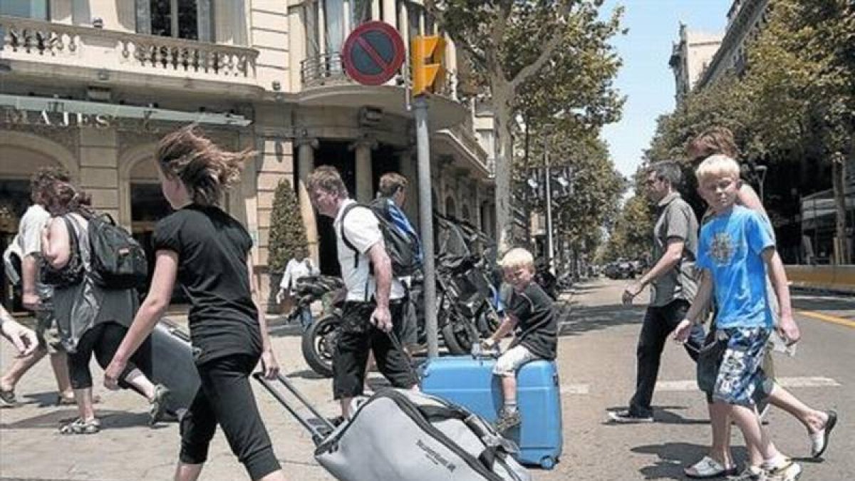 Turistas con maletas rumbo a su alojamiento recorren el paseo de Gràcia.