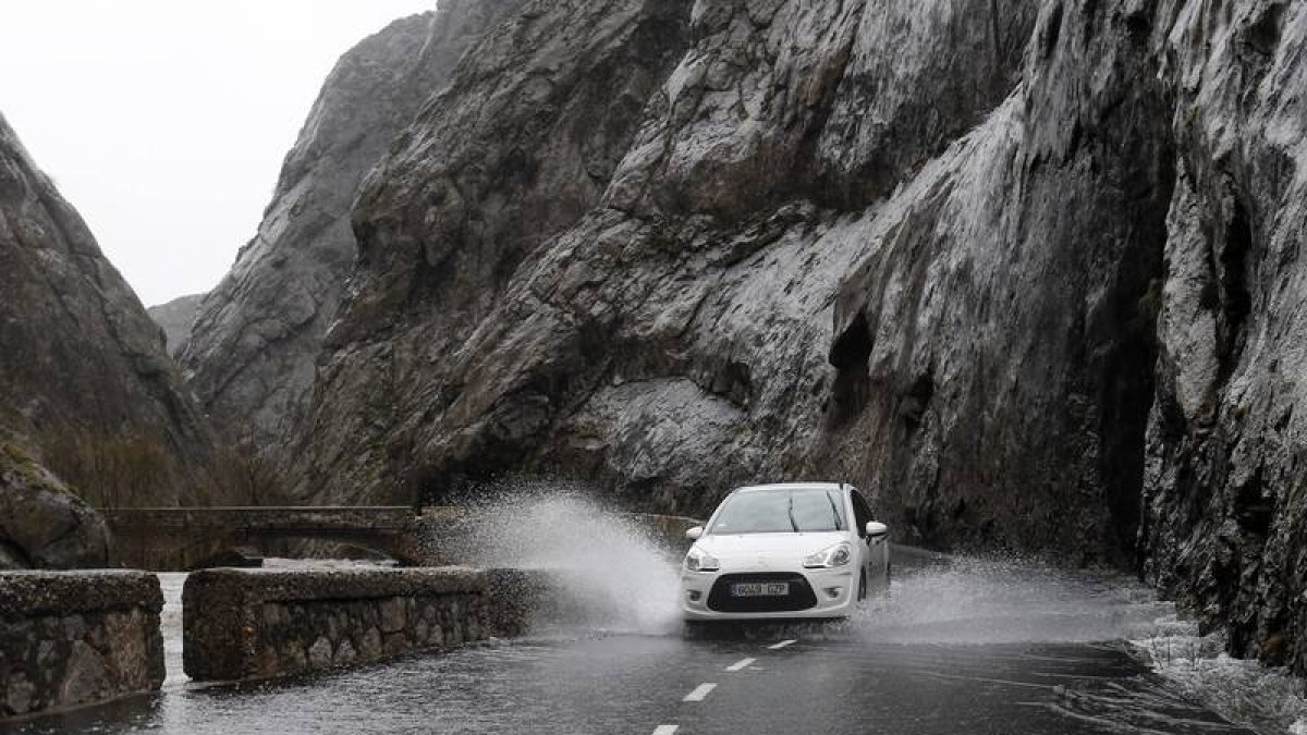 Un coche circula entre la lluvia en Vegacervera