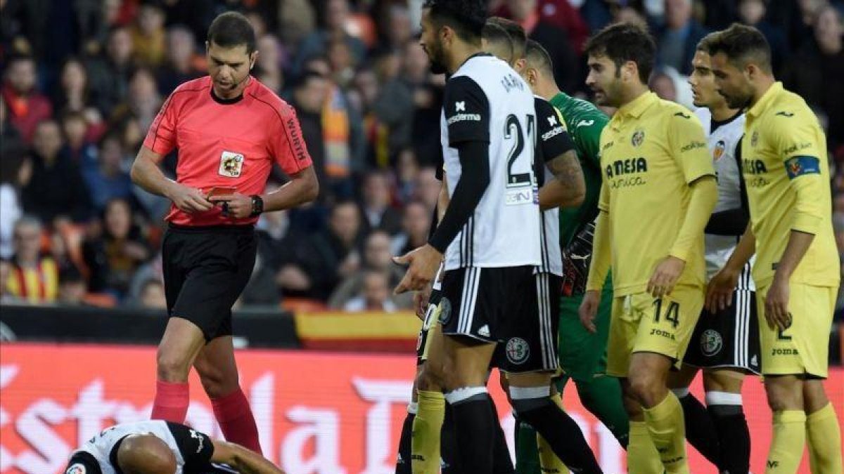El árbitro del Valencia-Villarreal se dirige a mostrar la segunda amarilla a Zaza, en el suelo.