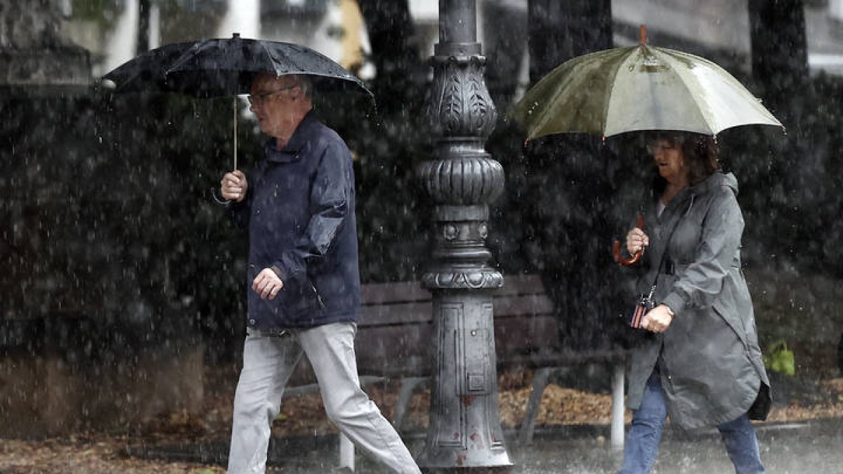 Dos personas se protegen de la lluvia con un paraguas. JESÚS DIGES