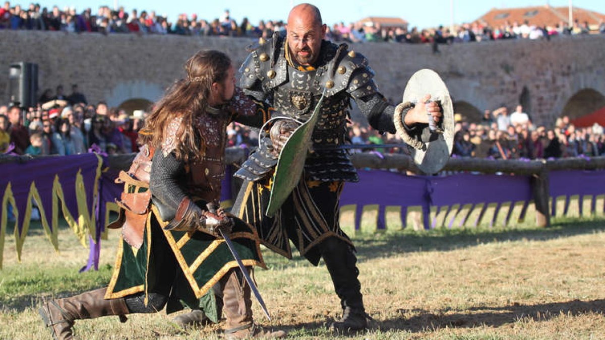 Dos de los caballeros participantes en las Justas del Passo Honroso mantienen un combate en presencia de numeroso público asistente a la fiesta.