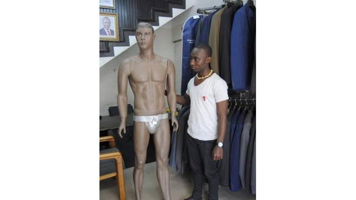 Un trabajador de la tienda Kings Castle de Nairobi posando con un maniquí y el cinturón de castidad.