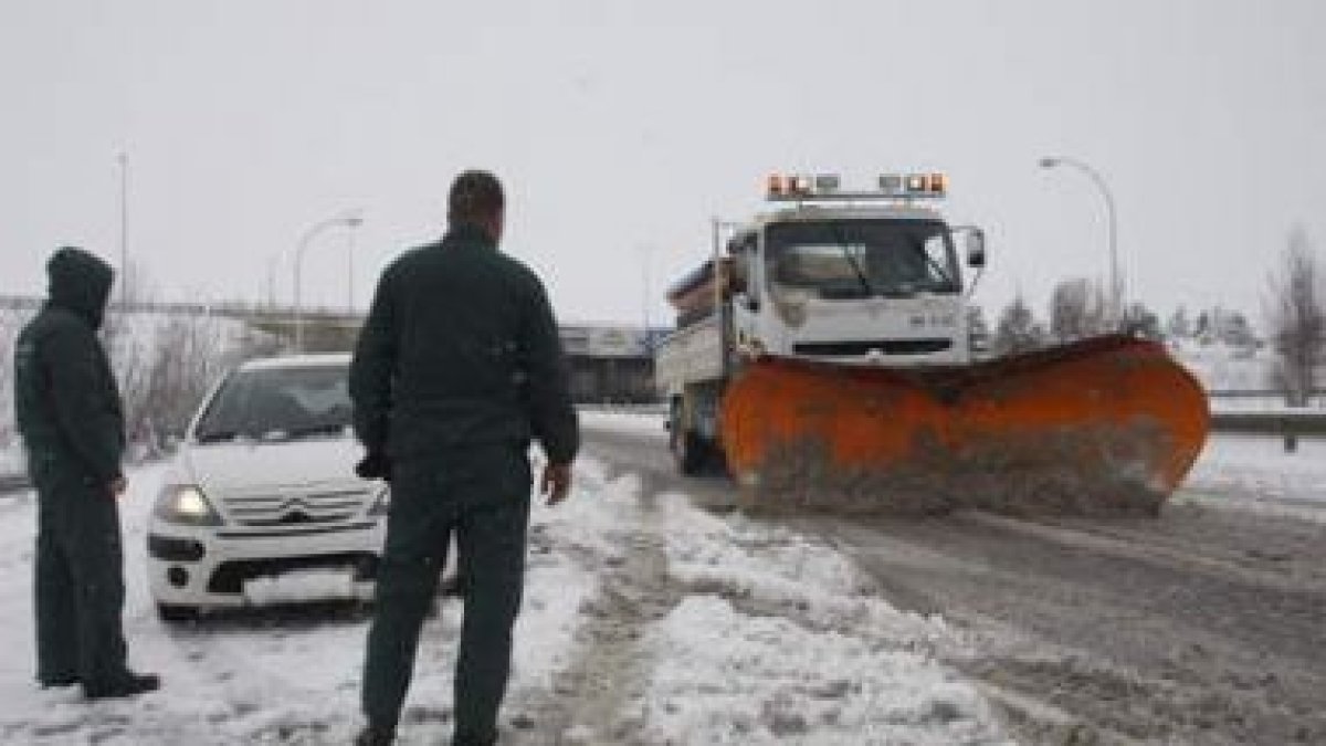 Una quitanieves trabaja en limpiar los accesos de la autopista, un vehículo espera a poder continuar