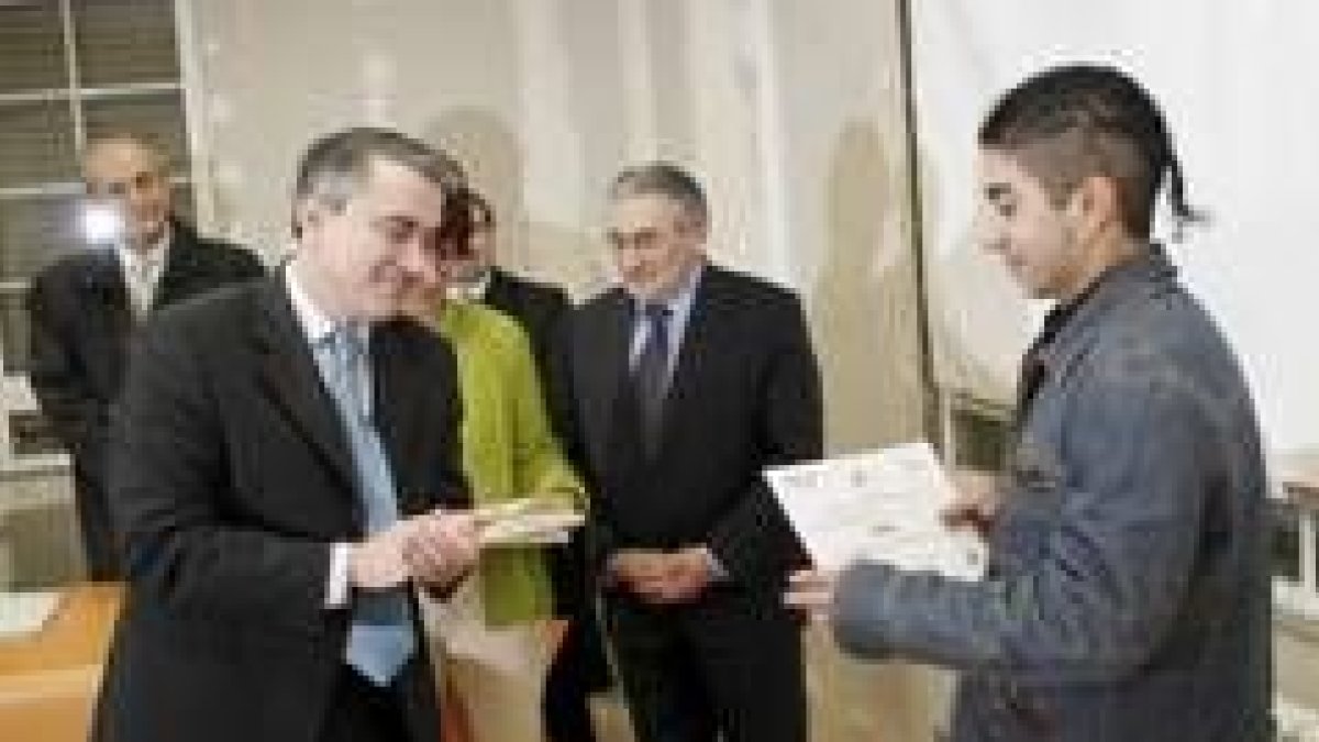 Gredilla entrega el diploma a un alumno, en presencia de Puente