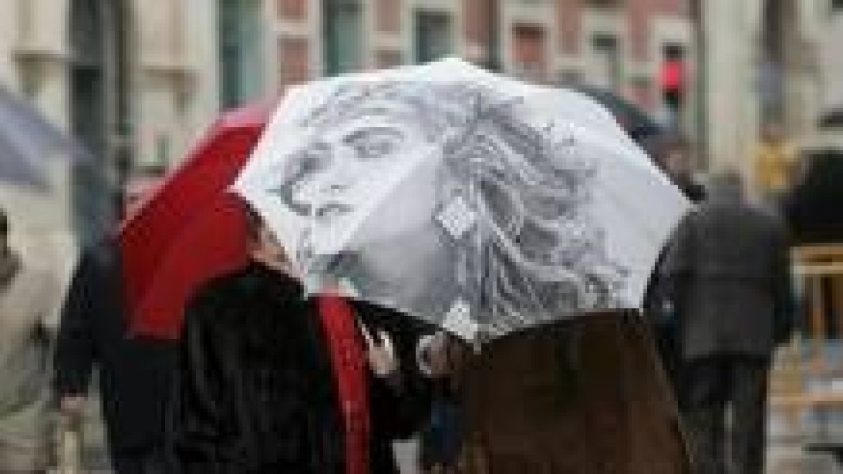 Dos mujeres se guarecen de la lluvia con un paraguas en la calle Ancha de León