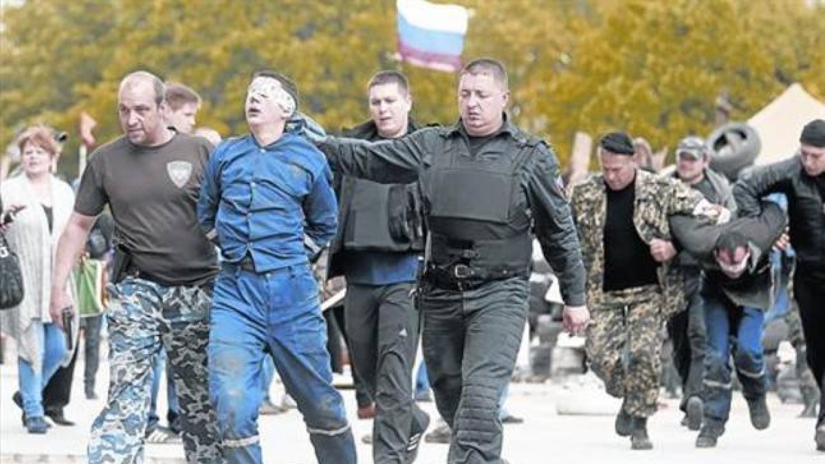 Unos prorrusos escoltan a dos hombres con los ojos vendados en Donetsk.