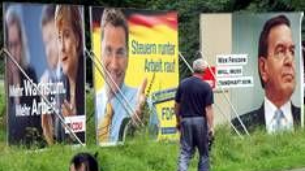 Un hombre pasea junto a varios carteles electorales de los candidatos