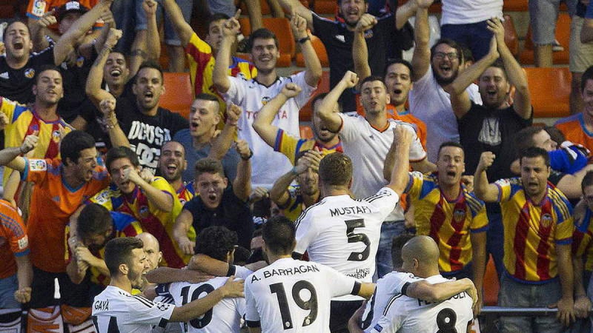 Los jugadores del Valencia celebran con sus aficionados la victoria ante el Mónaco.