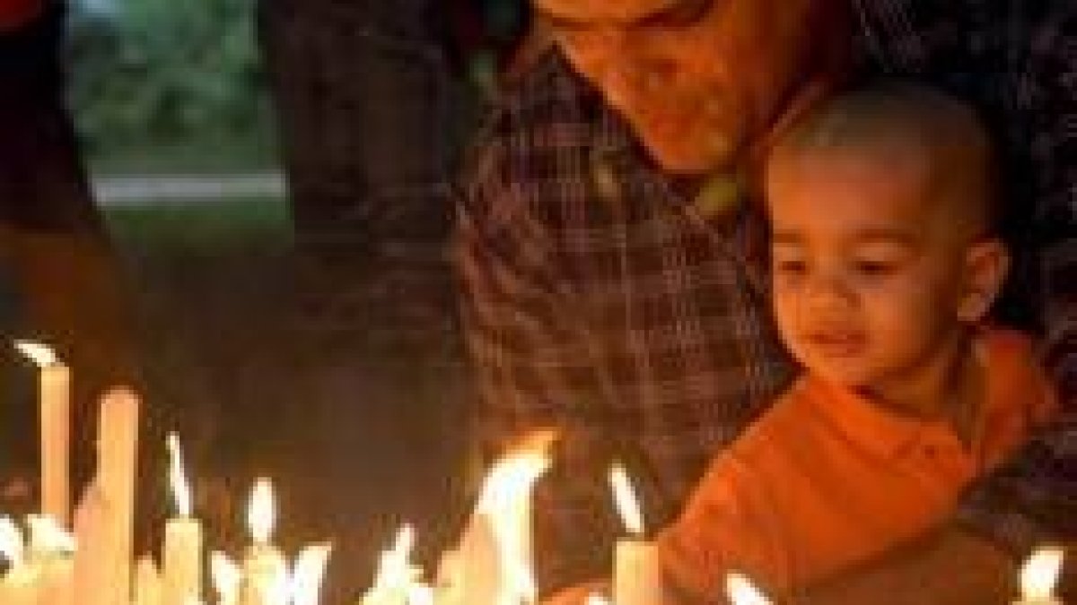 Un niño enciende una vela en memoria de los fallecidos por el atentado de Bombay el pasado 11-J