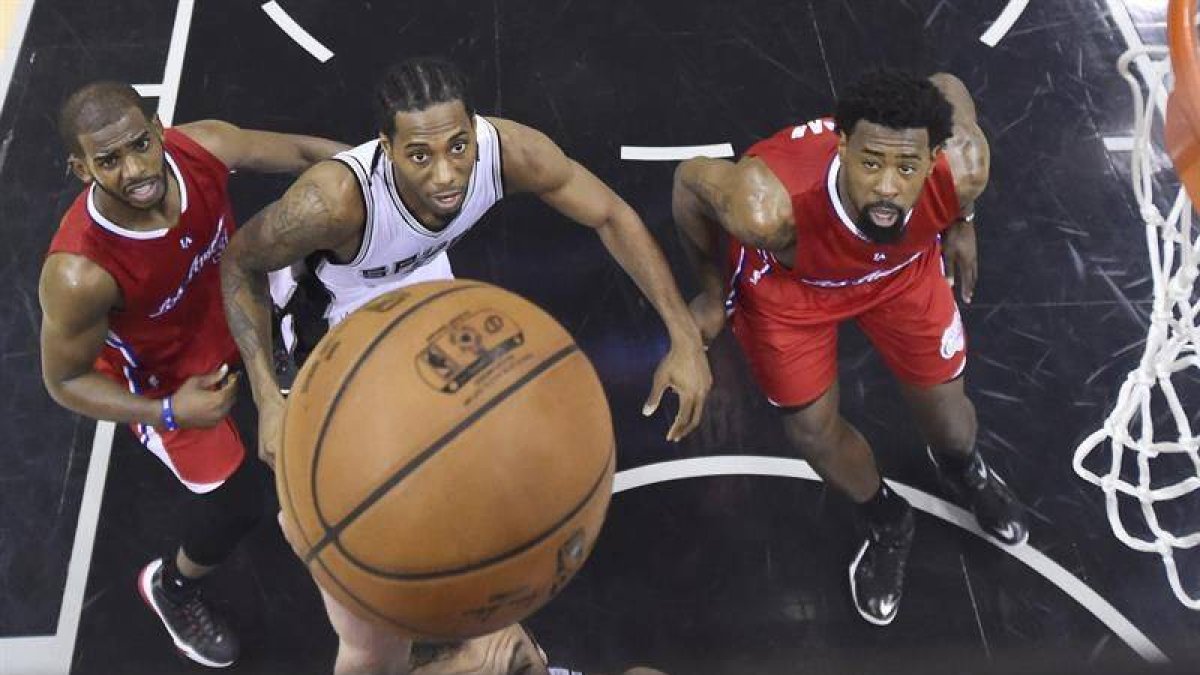 Chris Paul (L) and DeAndre Jordan lucha por un rebote con Kawhi Leonard.