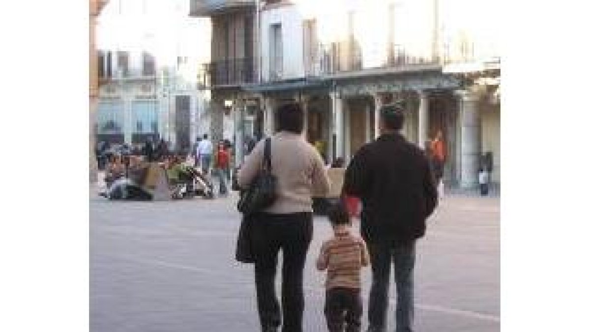 Una pareja camina en compañía de un niño por la plaza Mayor