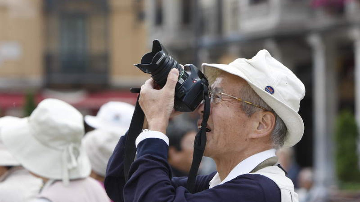 Un turista nipón fotografía la Catedral de León mientras su grupo atiende al guía.