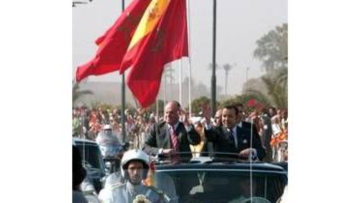 Don Juan Carlos y el rey de Marruecos saludan al público en su recorrido hasta el Palacio Real