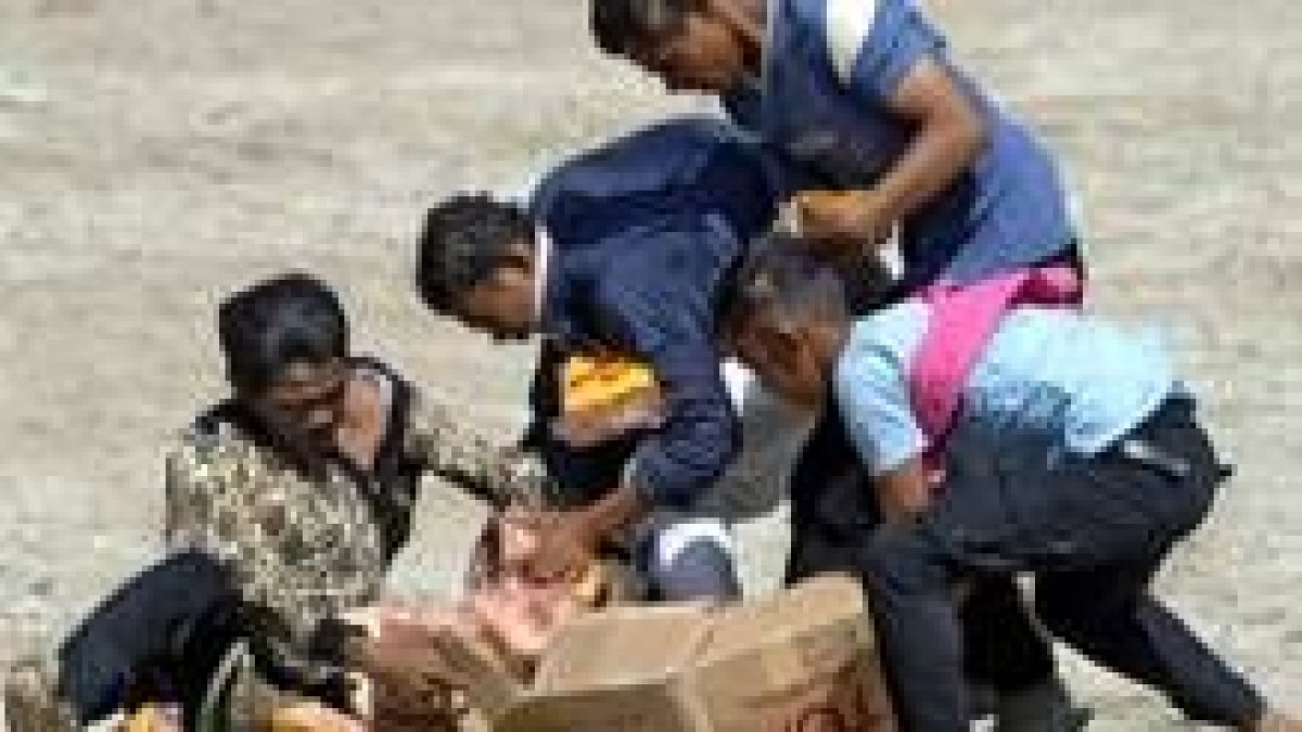 Refugiados indonesios se reparten un lote de comida