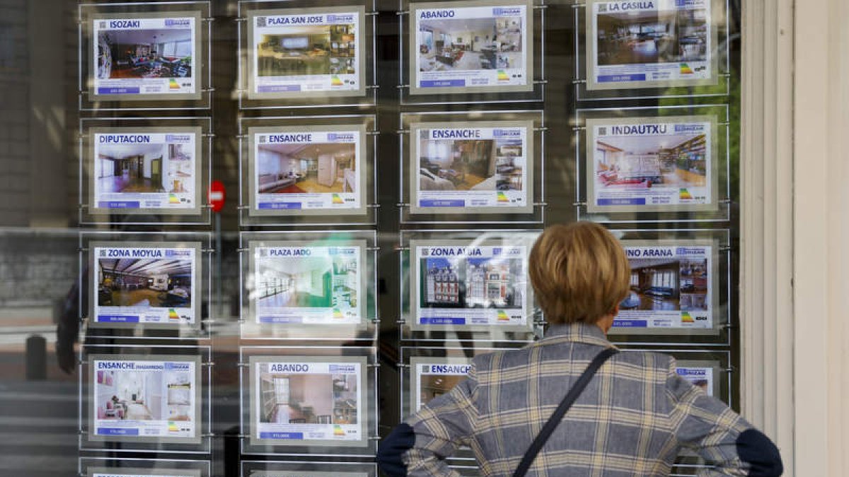 Una mujer mira los precios de los pisos en el escaparate de una inmobiliaria. LUIS TEJIDO