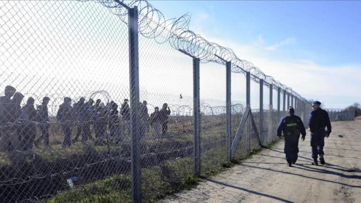 Un grupo de refugiados pasa por la valla que separa a Hungría de Serbia.