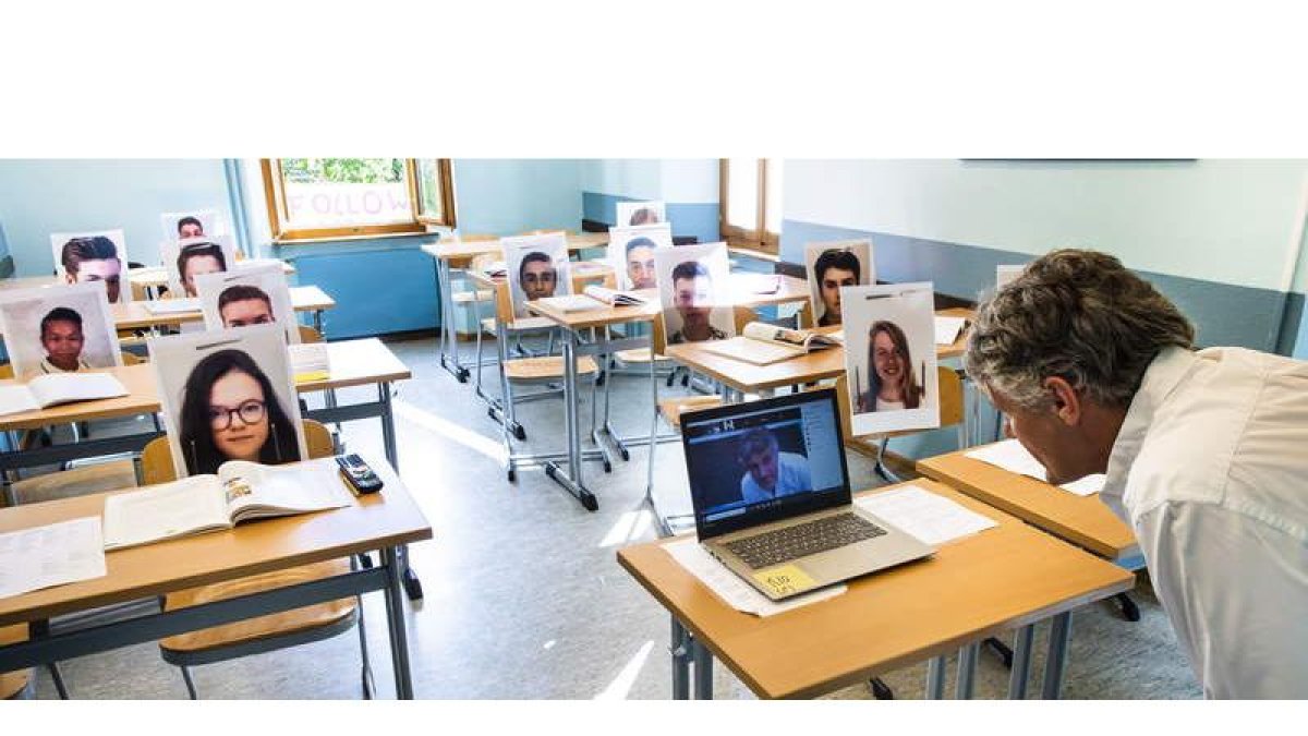 Un profesor imparte clase de manera virtual pero con la foto de cada uno de sus alumnos en el pupitre correspondiente. BOTT
