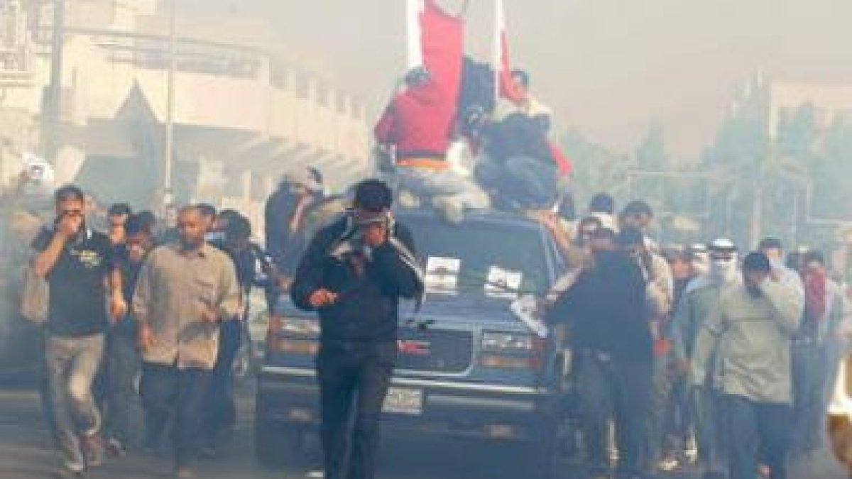 Manifestantes se cubren del gas lacrimógeno mientras escoltan el coche fúnebre de Ali Abdul Mushima.