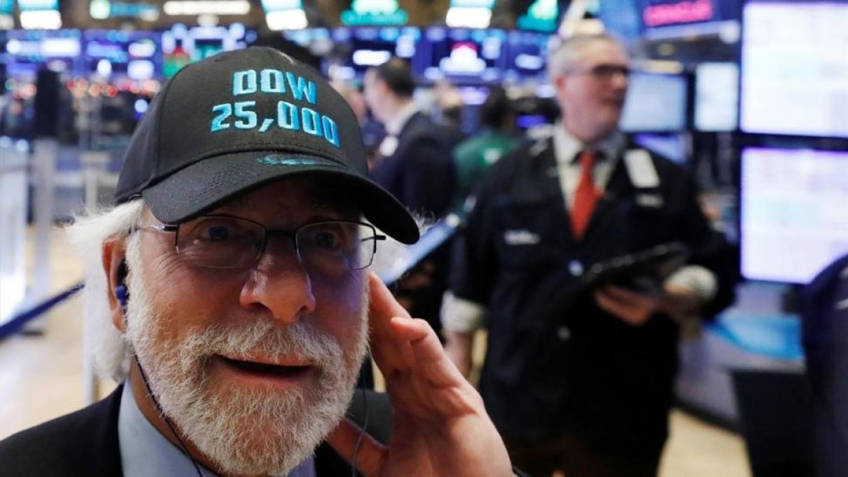 Un operador de Wall Street luce una gorra conmemorativa de los 25.000 puntos alcanzados por el Dow Jones.
