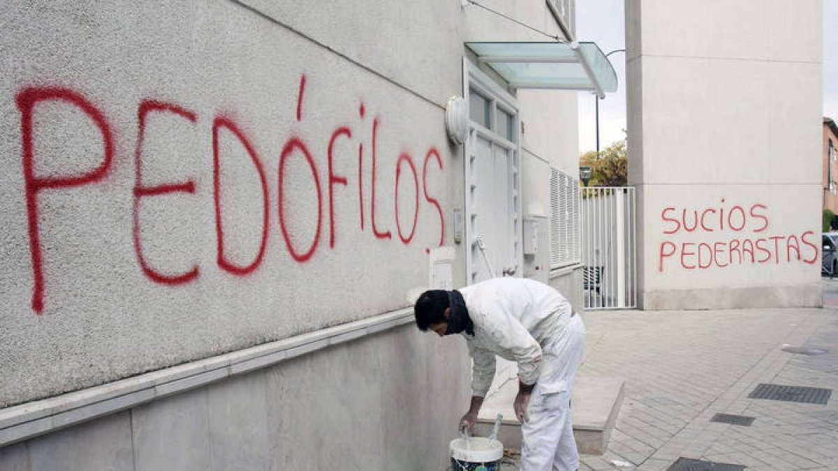 Un pintor repasa con pintura blanca una pintadas con acusaciones de pedofilia y pederastia en una parroquia de Granada. PEPE TORRES