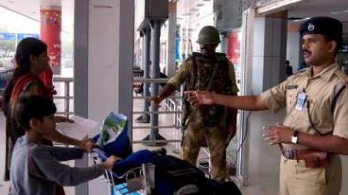 Personal de seguridad aeroportuario da indicaciones a un par de viajeros en el aeropuerto de Chennai
