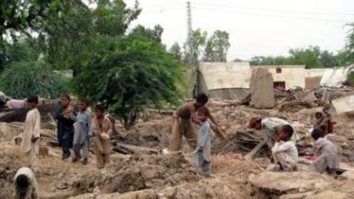 Niños buscan sus pertenencias entre los restos de sus casas devastadas en Pakistán.