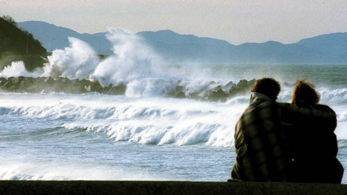 Una pareja mira las olas en San Sebastián.