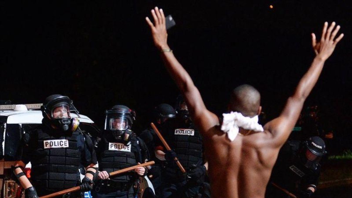 Un joven levanta los brazos ante la policía en Charlotte.