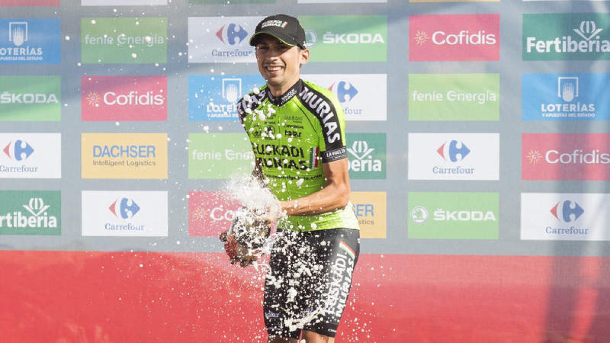 Óscar Rodríguez celebra en el podio su épico triunfo en el alto de La Camperona. FERNANDO OTERO