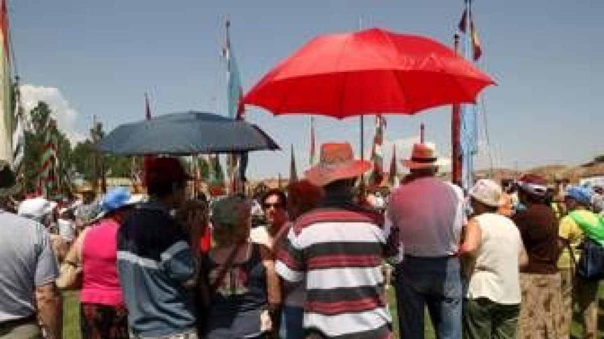 Varias personas se protegen con paraguas en el campo en Jiménez de Jamuz