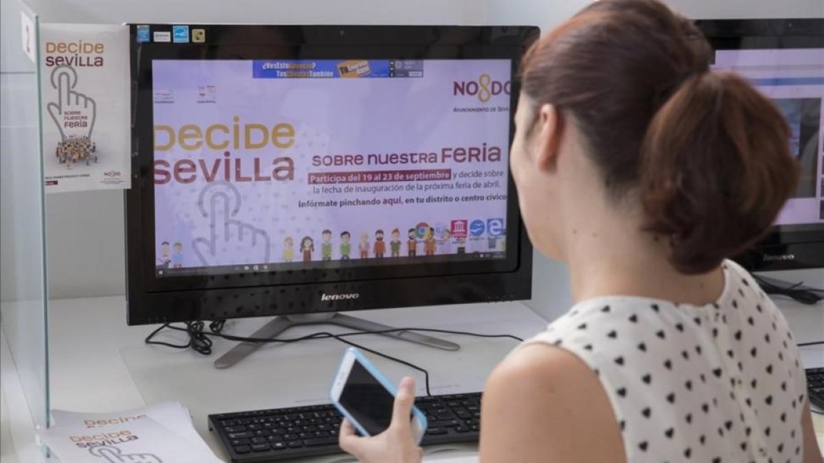 Una empleada del Ayuntamiento de Sevilla ante la web abierta para votar sobre la duración de la Feria de Abril.