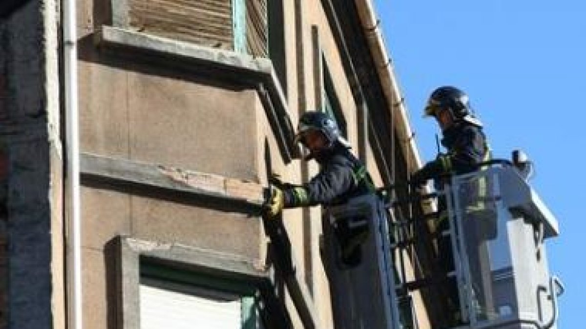 Dos bomberos de Ponferrada trabajan en las labores de retirada de cascotes, ayer en la avenida Valdé