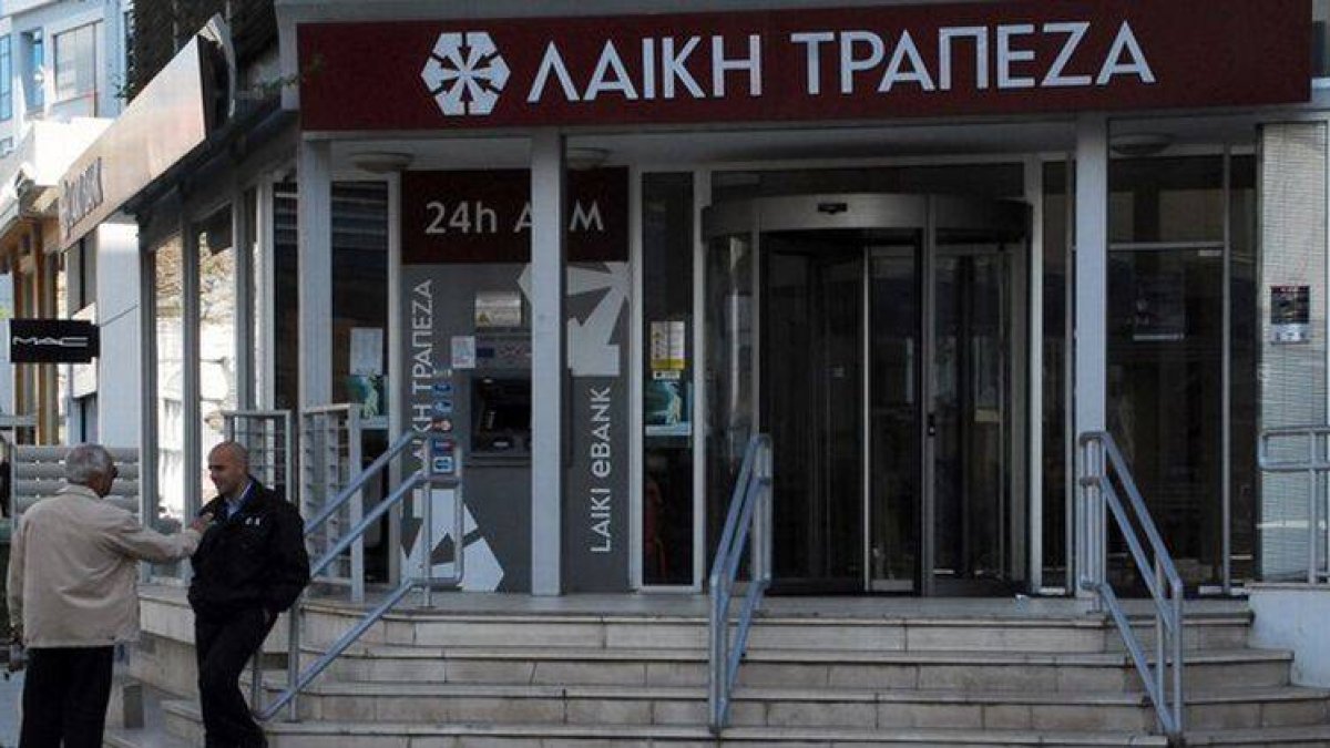 Un hombre habla con un guardia de seguridad en las puertas del Banco Laiki, en Nicosia, antes de su apertura.